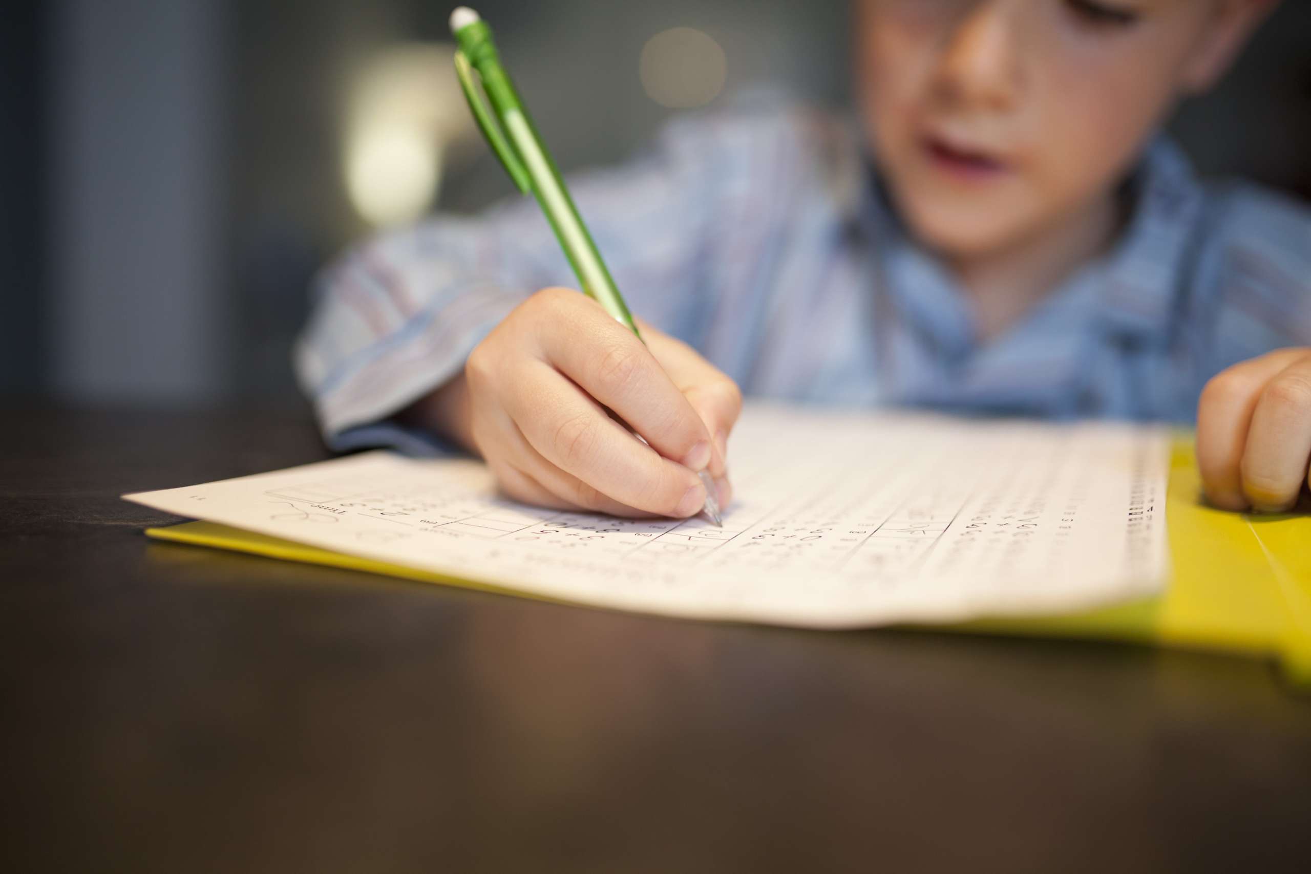 Ein Junge löst Hausaufgaben und schreibt die Lösungen in ein Heft.
